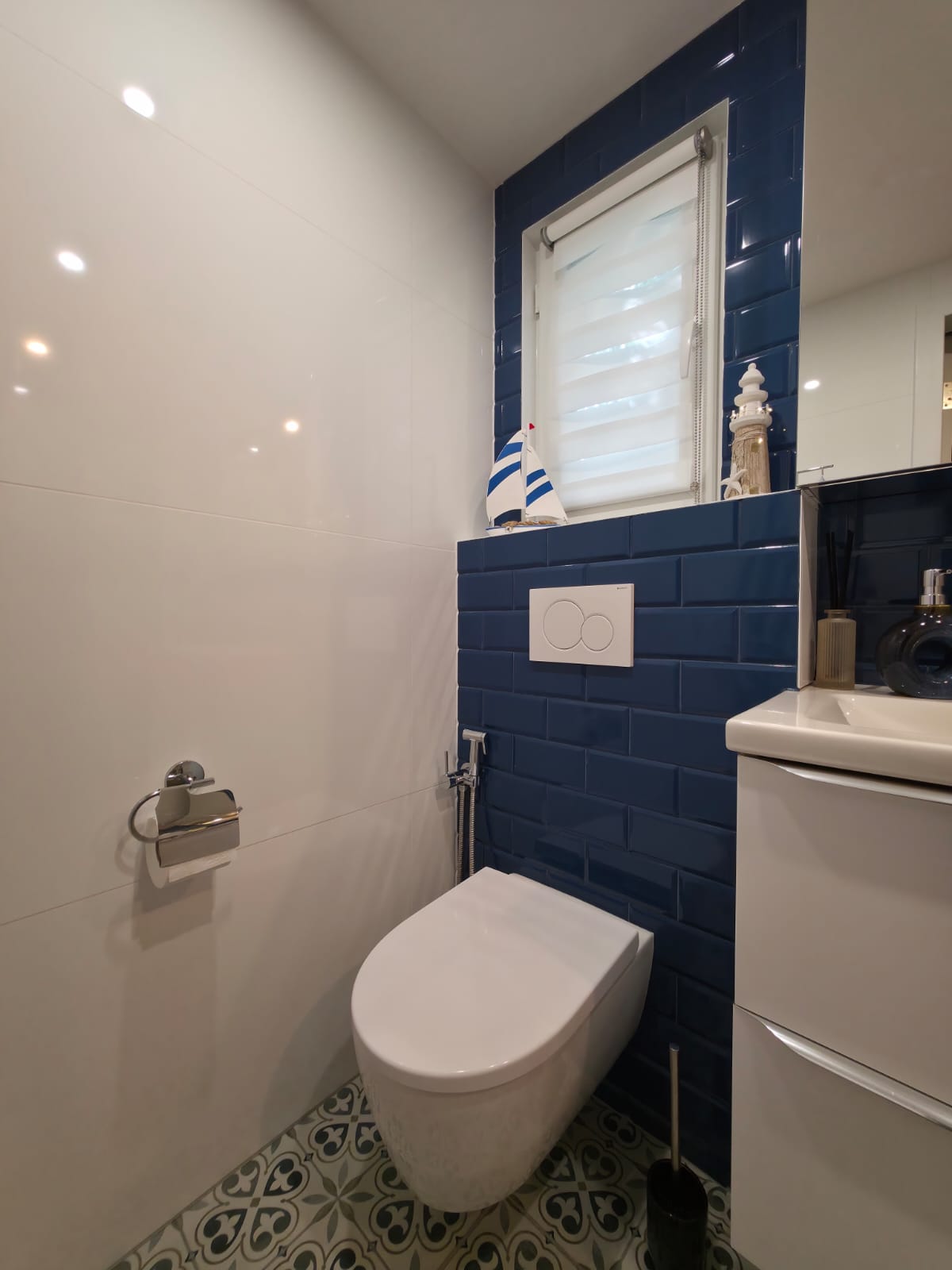 Bathroom with white wall tiles and dark-blue tiled feature wall around window and toilet