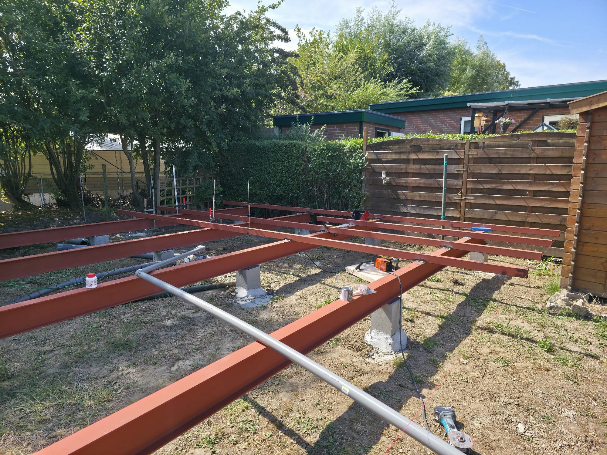 Red steel base frame being mounted on concrete foundation piers