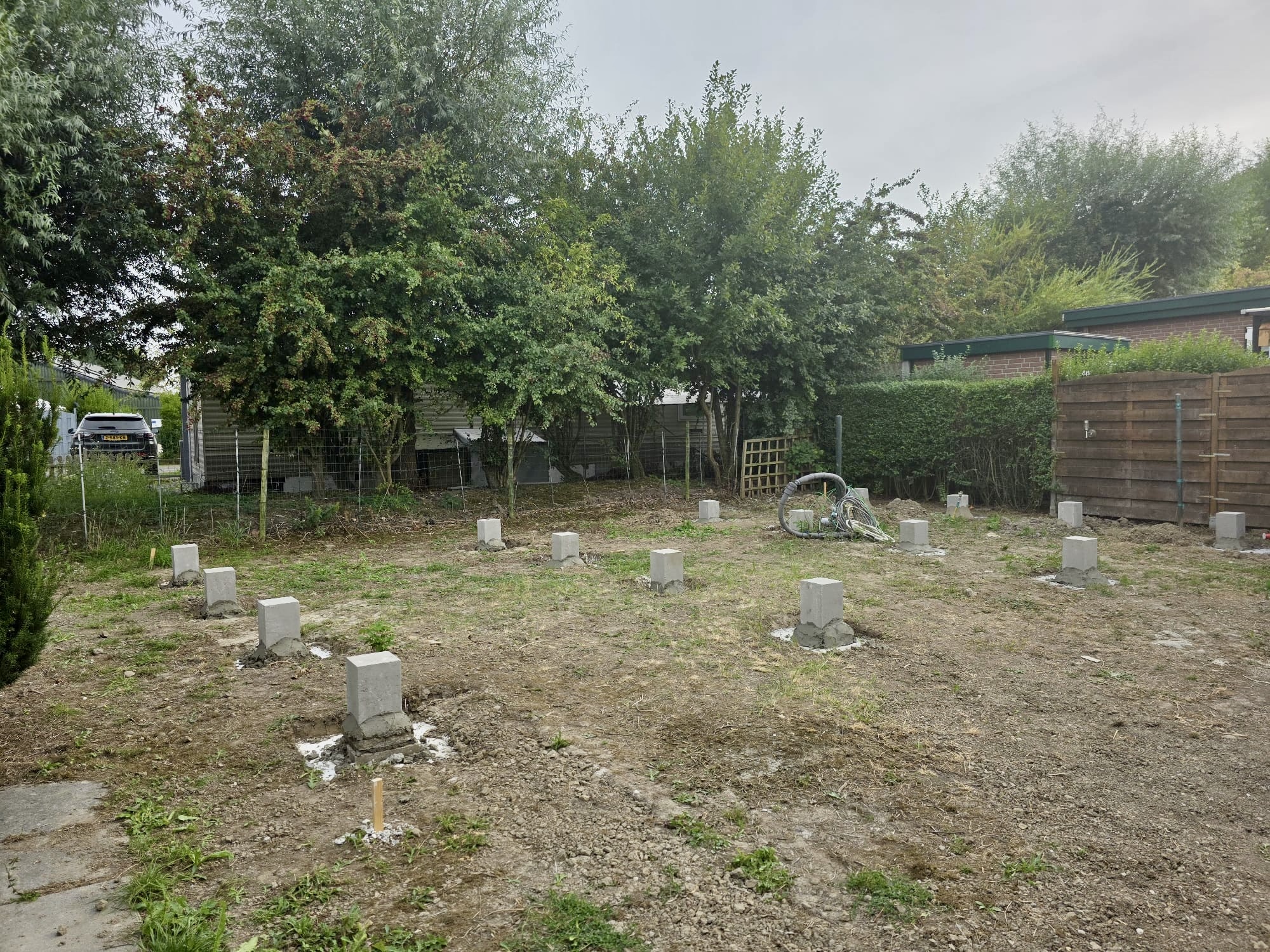 Row of poured concrete foundation piers set out across a building plot