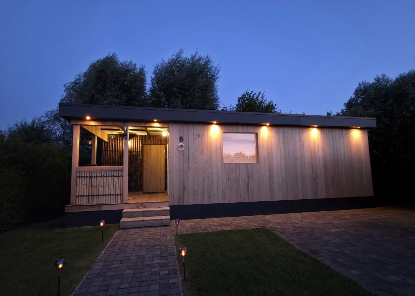Final night view of the completed timber building and landscaped path