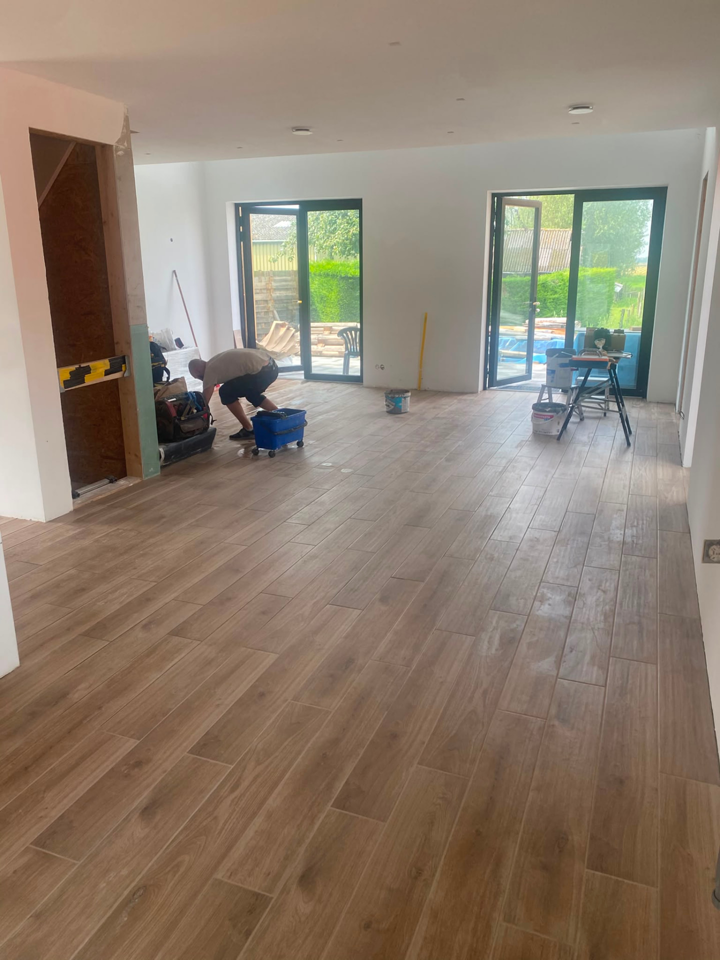 Spacious living room with newly installed light wood-look tiles and garden doors