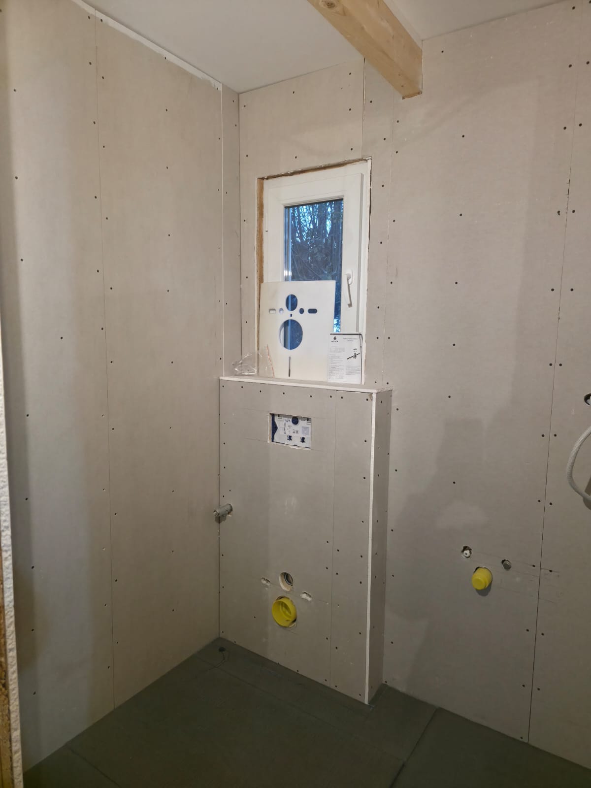 Bathroom drywall with concealed toilet frame, window and plumbing connections