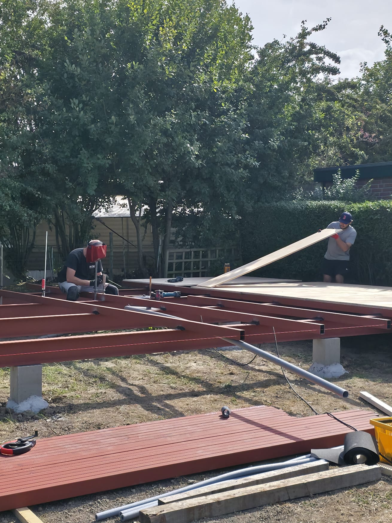Workers welding the steel frame and laying the first floor boards