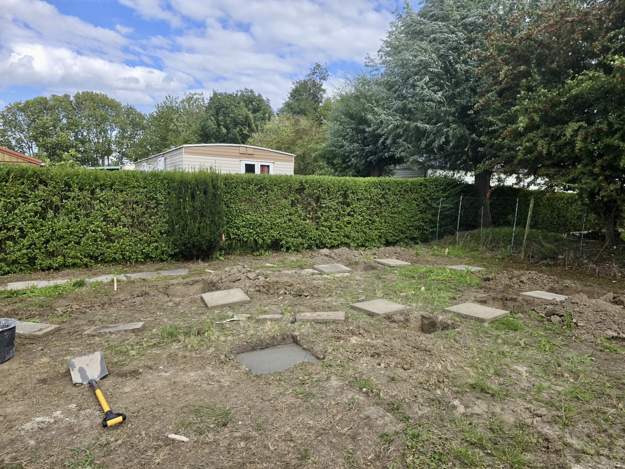 Building plot with foundation holes and concrete pads prepared for a new garden house