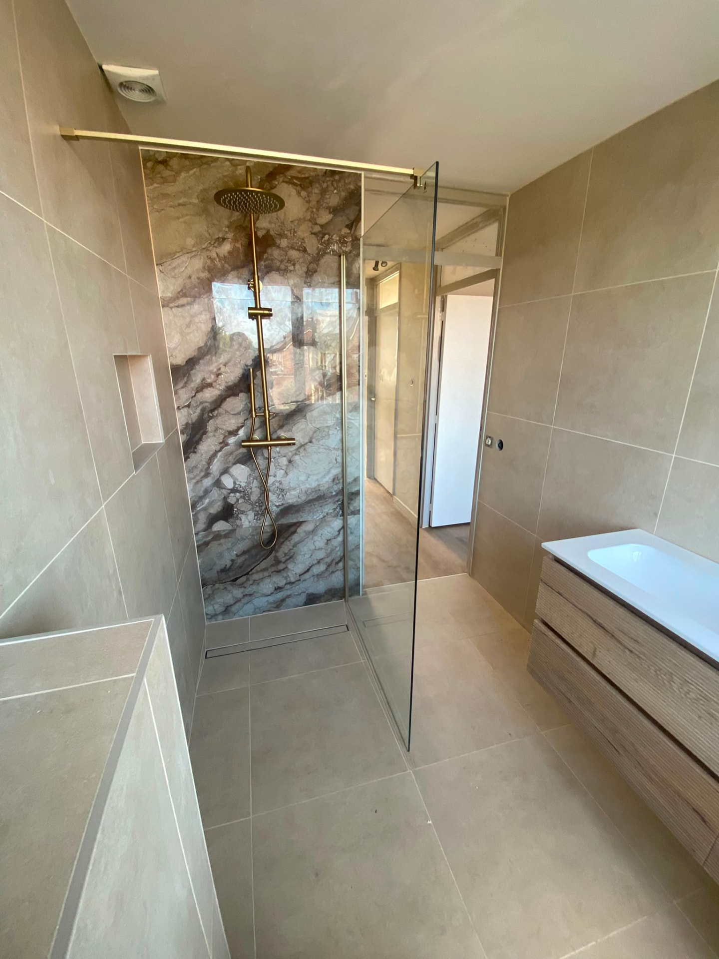 Neutral beige bathroom with marble-effect shower and gold fixtures