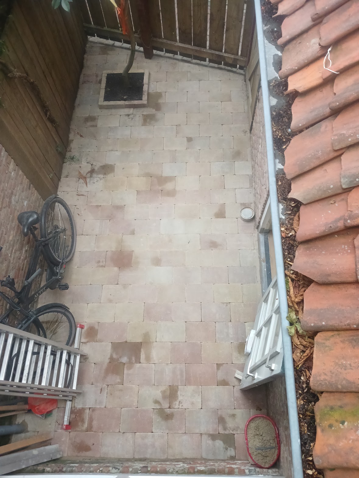 Narrow outdoor passage paved with light stone pavers alongside a brick wall