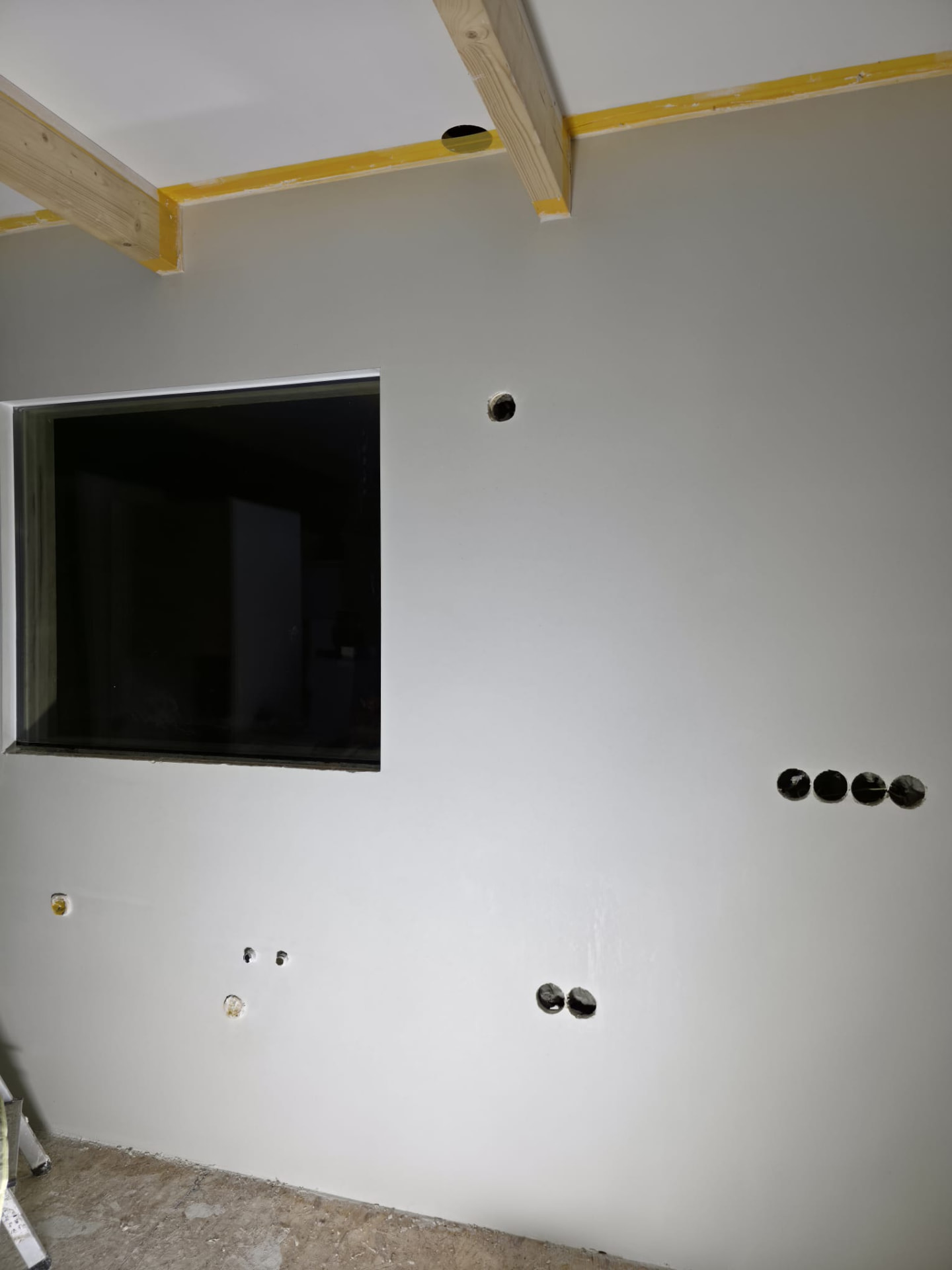 Plasterboard room with electrical outlet cutouts, window and ceiling beam