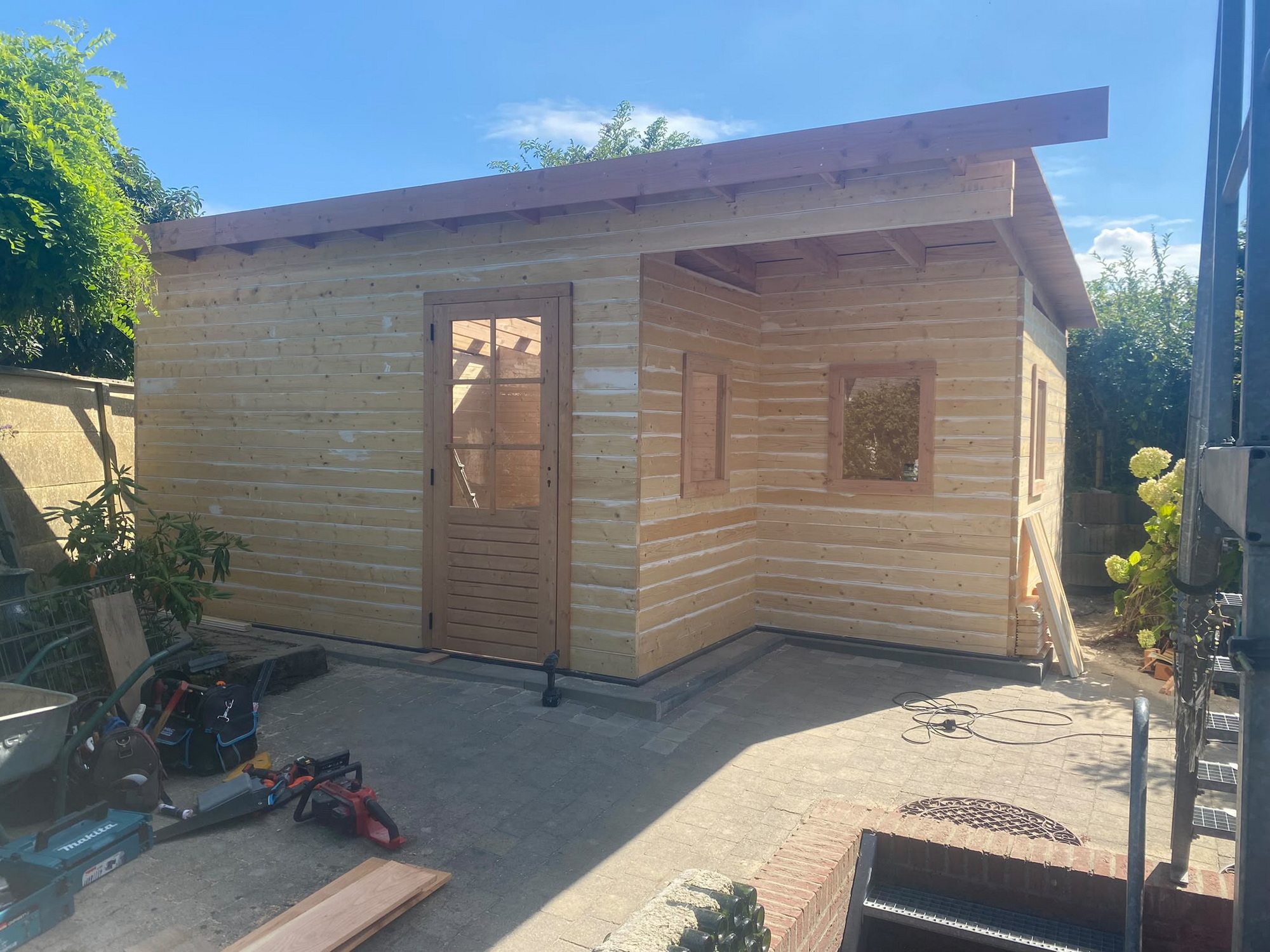 Timber-clad outbuilding with windows, door and covered porch