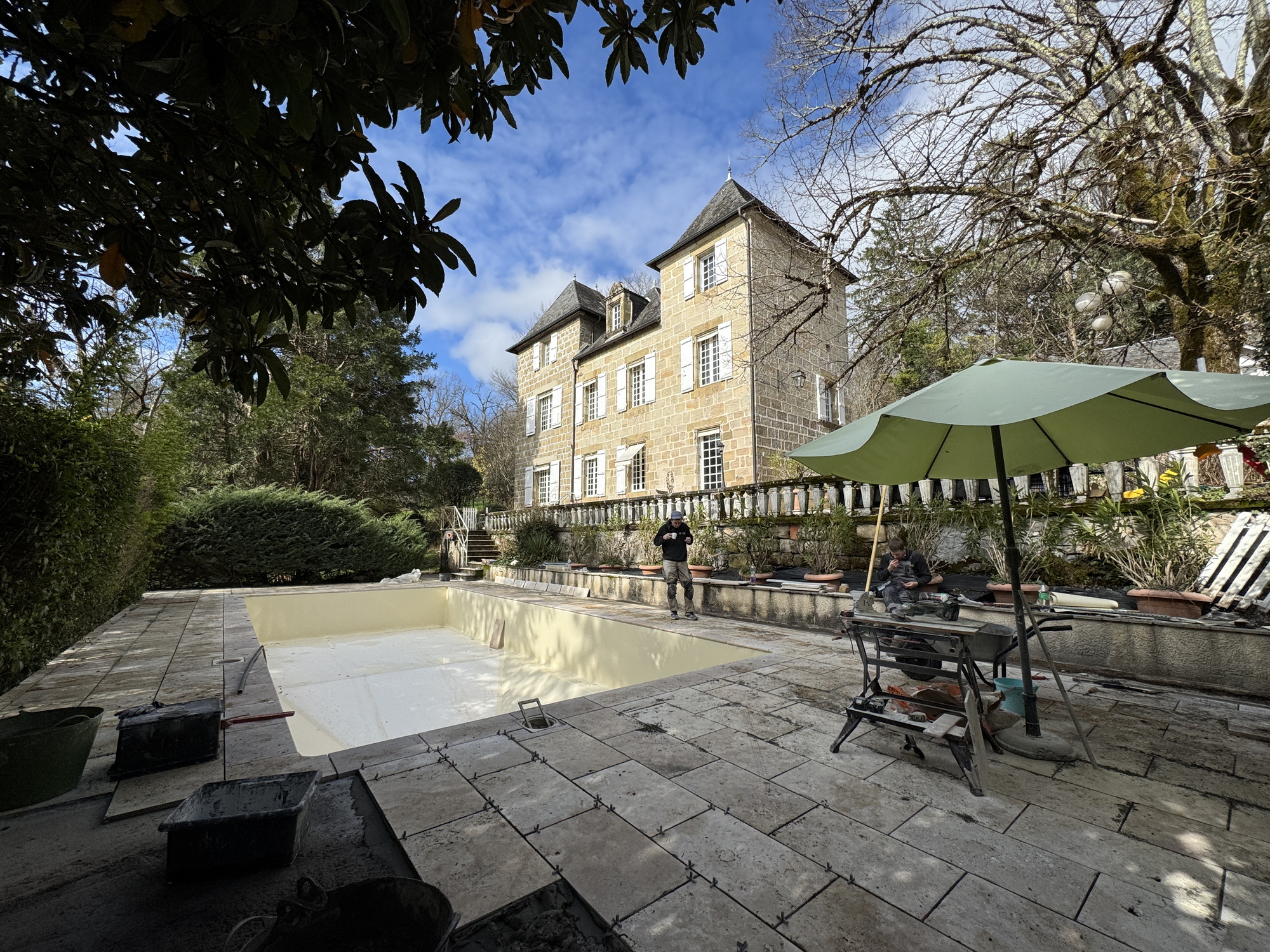 Stone terrace paving being laid around a renovated swimming pool