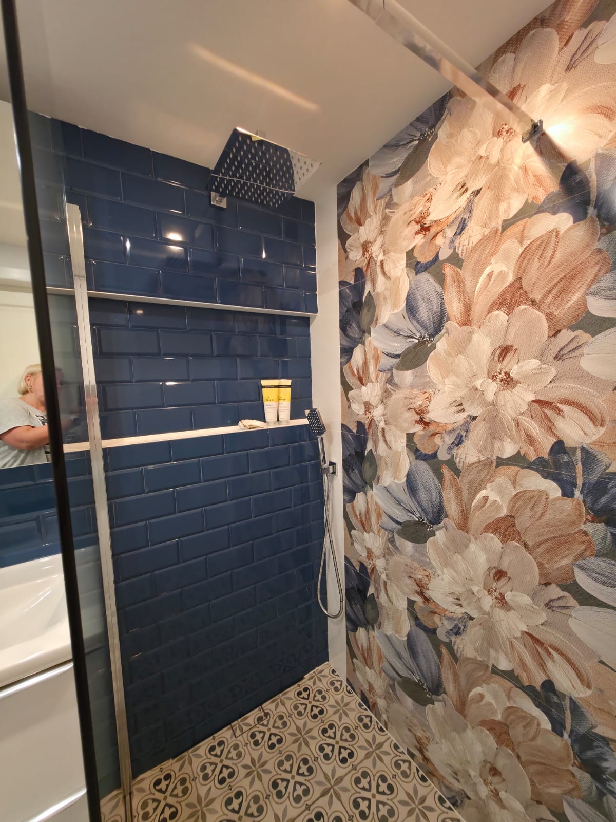 Finished bathroom with dark-blue wall tiles, floral shower feature and patterned floor