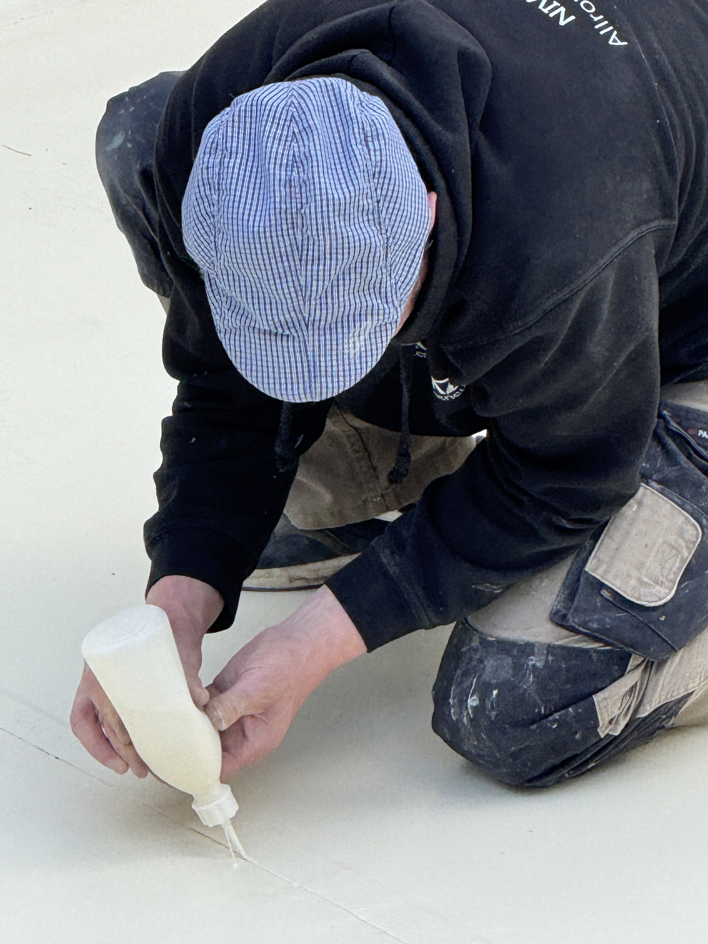 Worker applying sealant to a pool surface during renovation