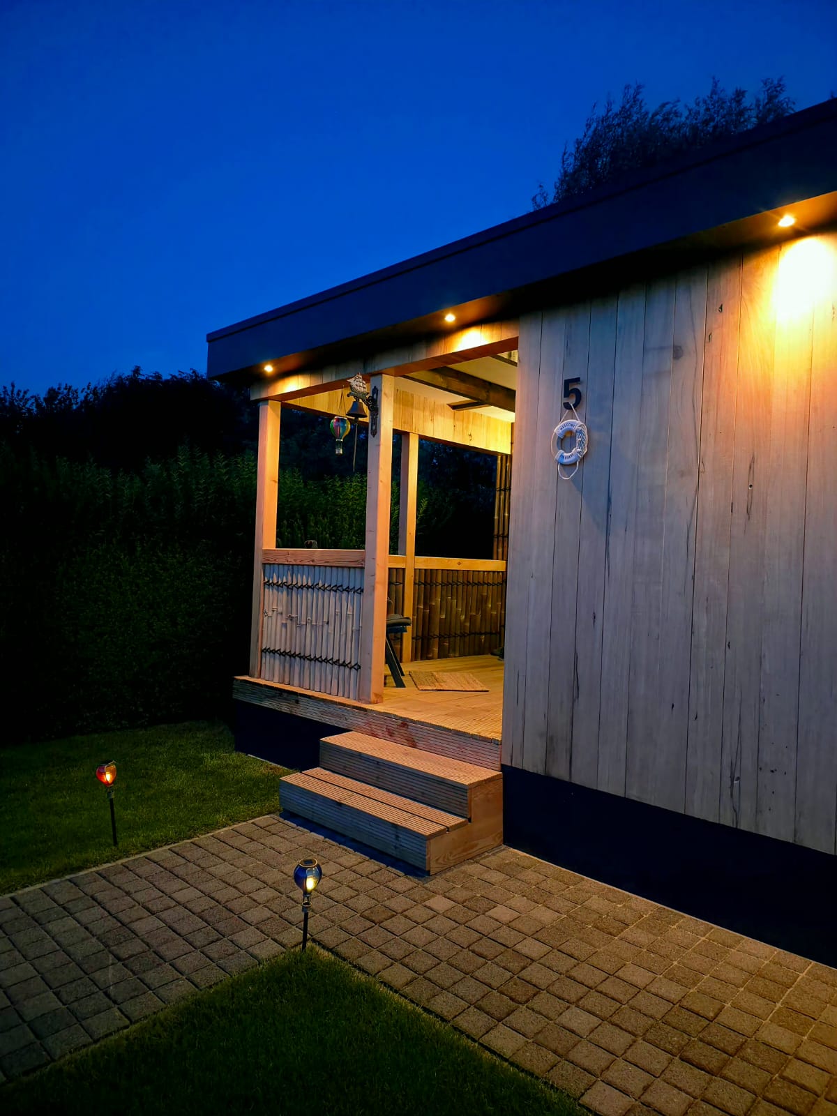 Completed timber exterior with porch steps and integrated lighting at dusk