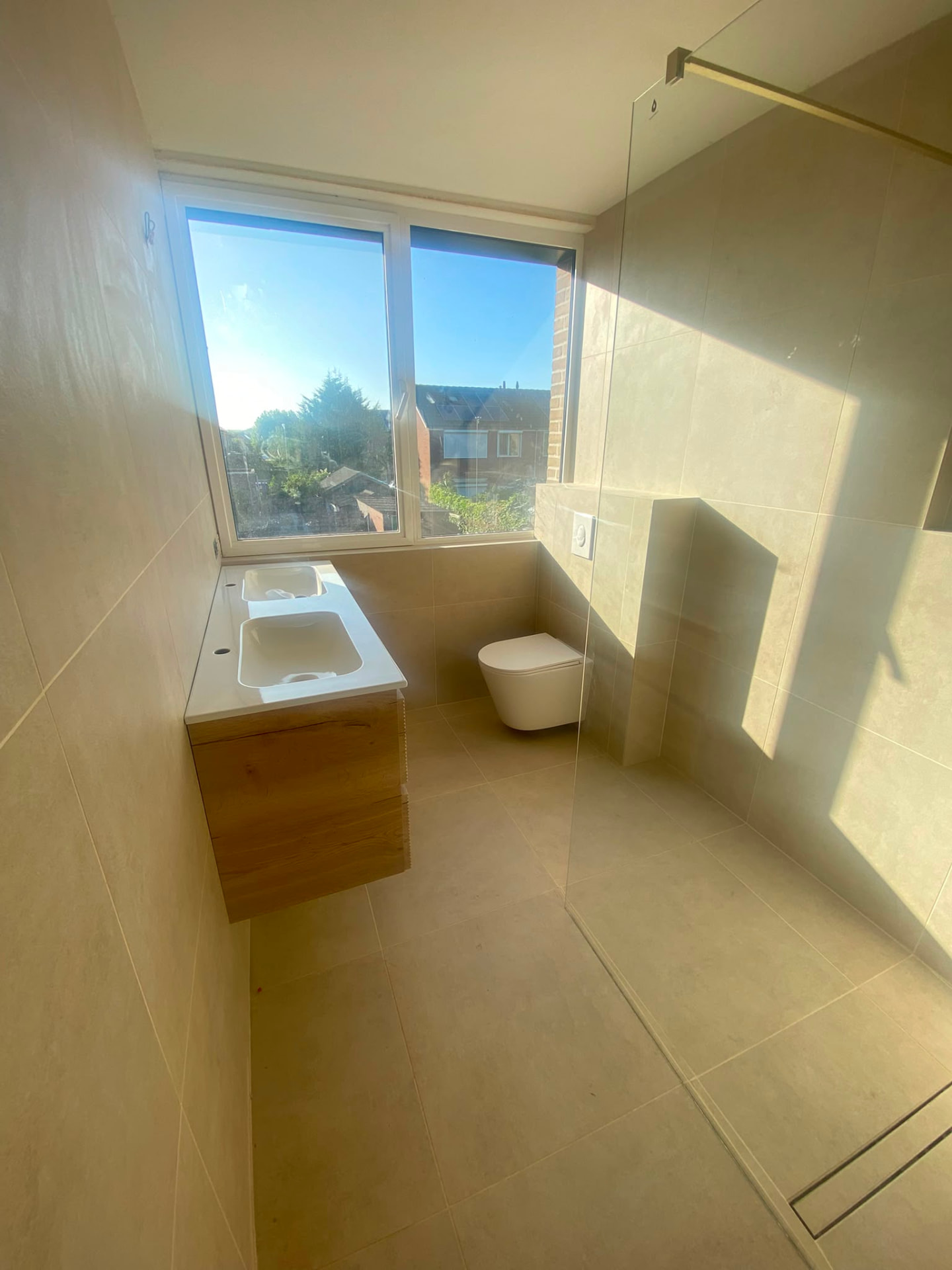 Renovated en-suite bathroom with tiled walls, double vanity and walk-in shower glass