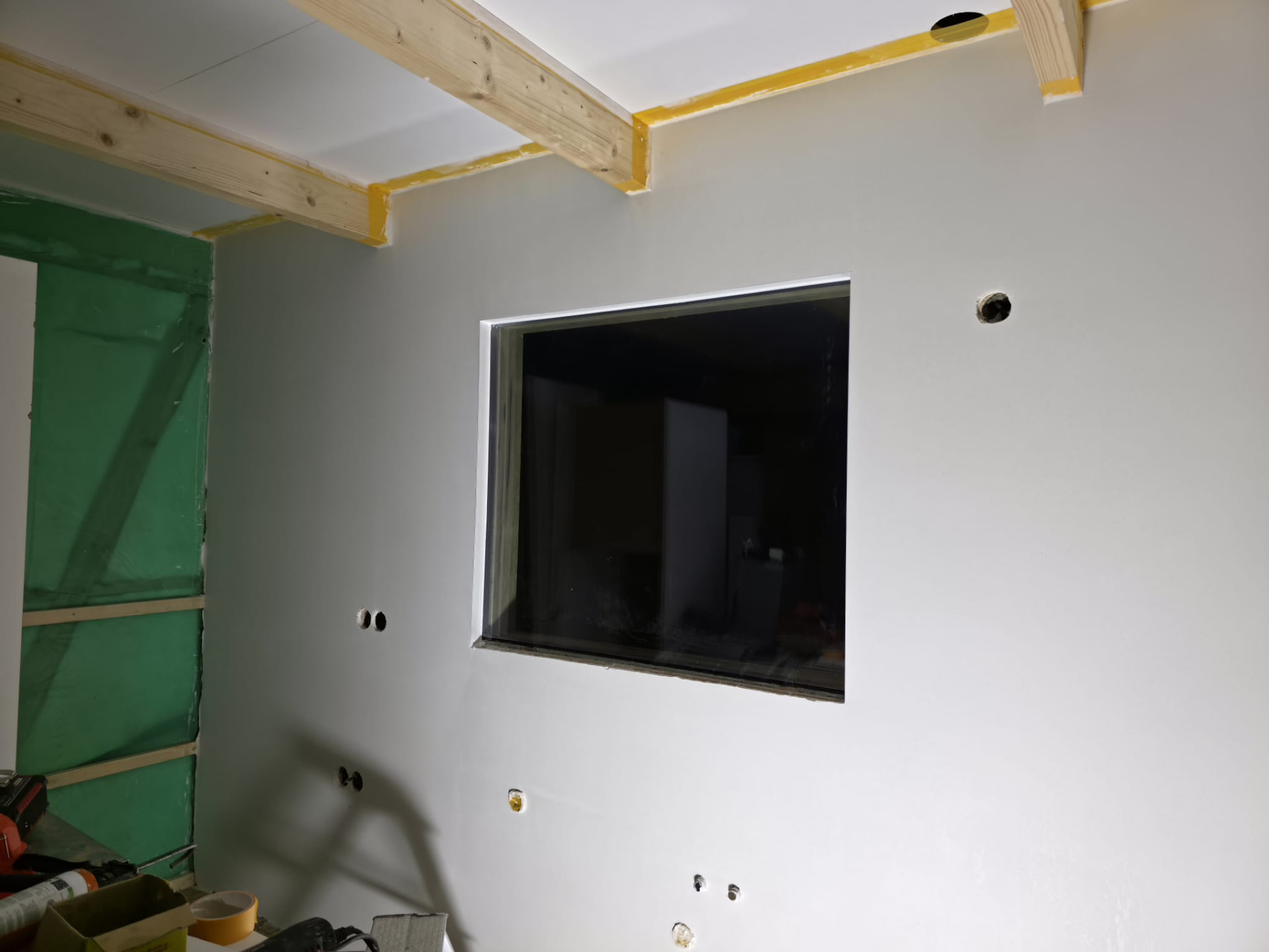 Room with plasterboard walls, window and green protection sheeting during finishing