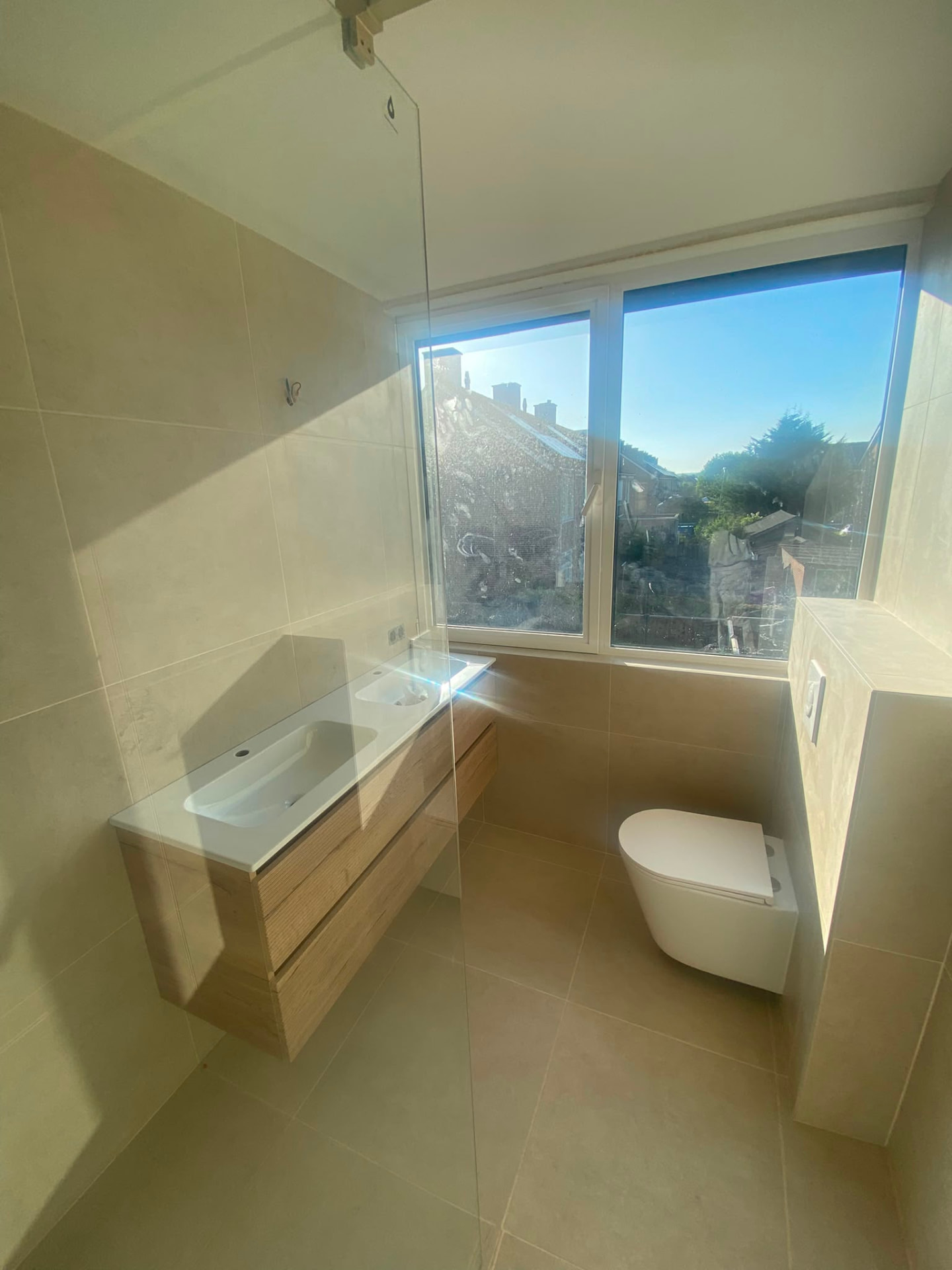 Newly renovated bathroom with large window, wall-hung vanity and toilet