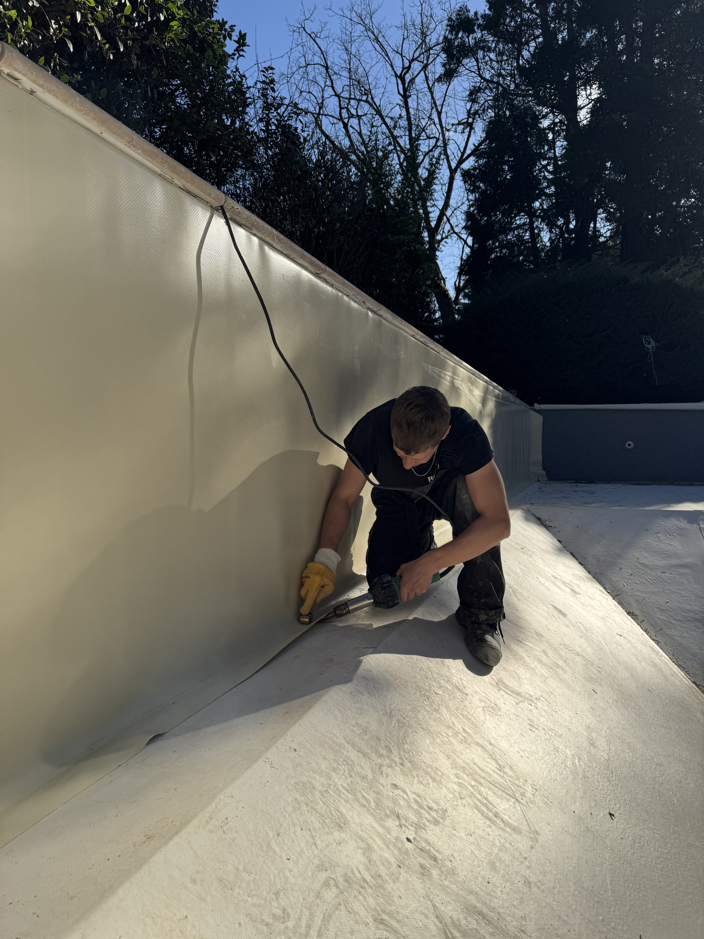 Worker fitting a new white pool liner inside a renovated swimming pool