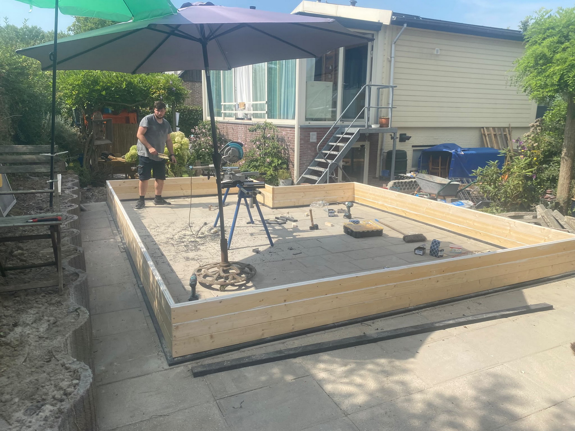 Timber perimeter walls being assembled on an existing paved base