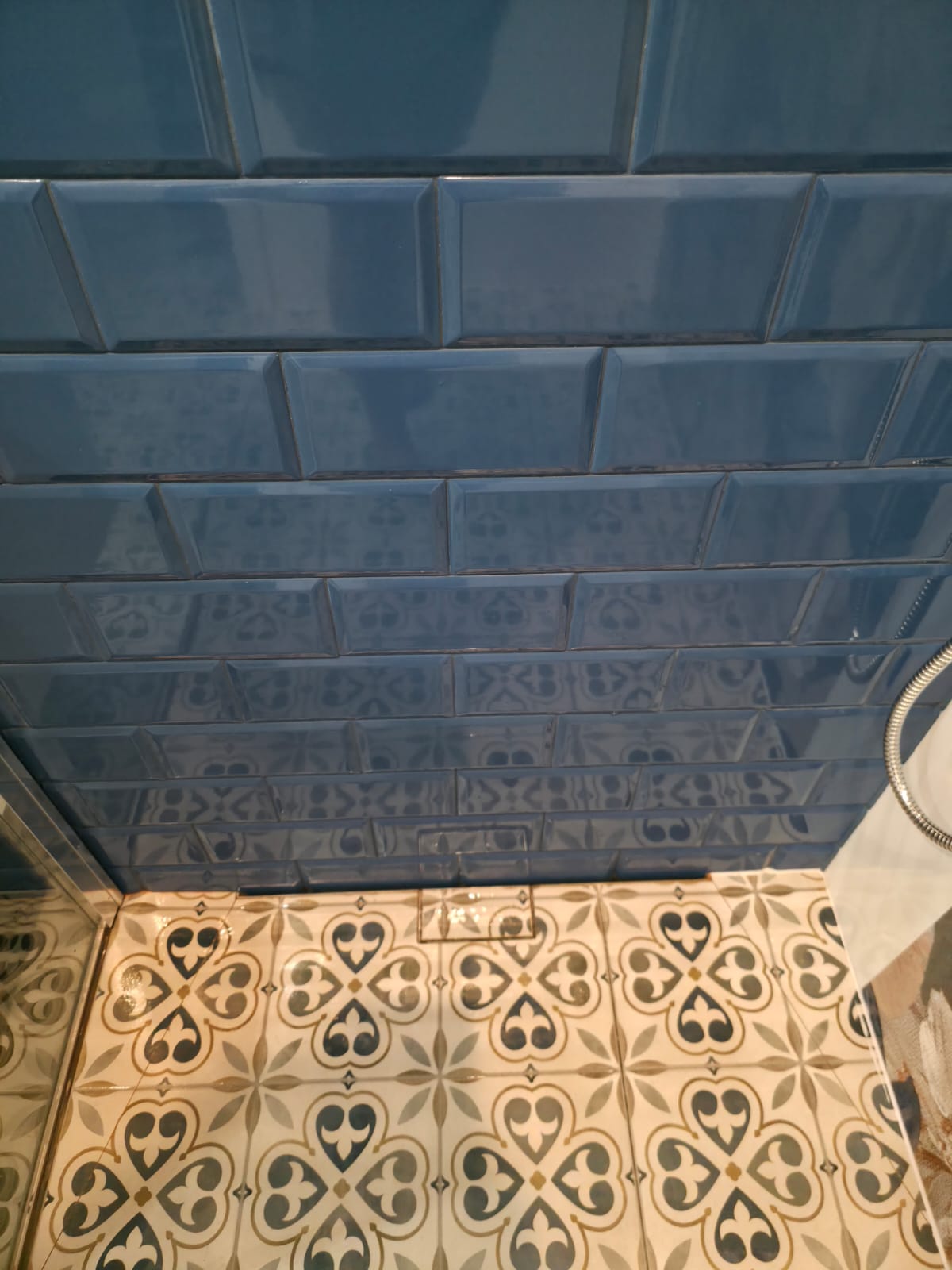 Close-up of glossy dark-blue brick-pattern wall tiles above patterned floor tiles