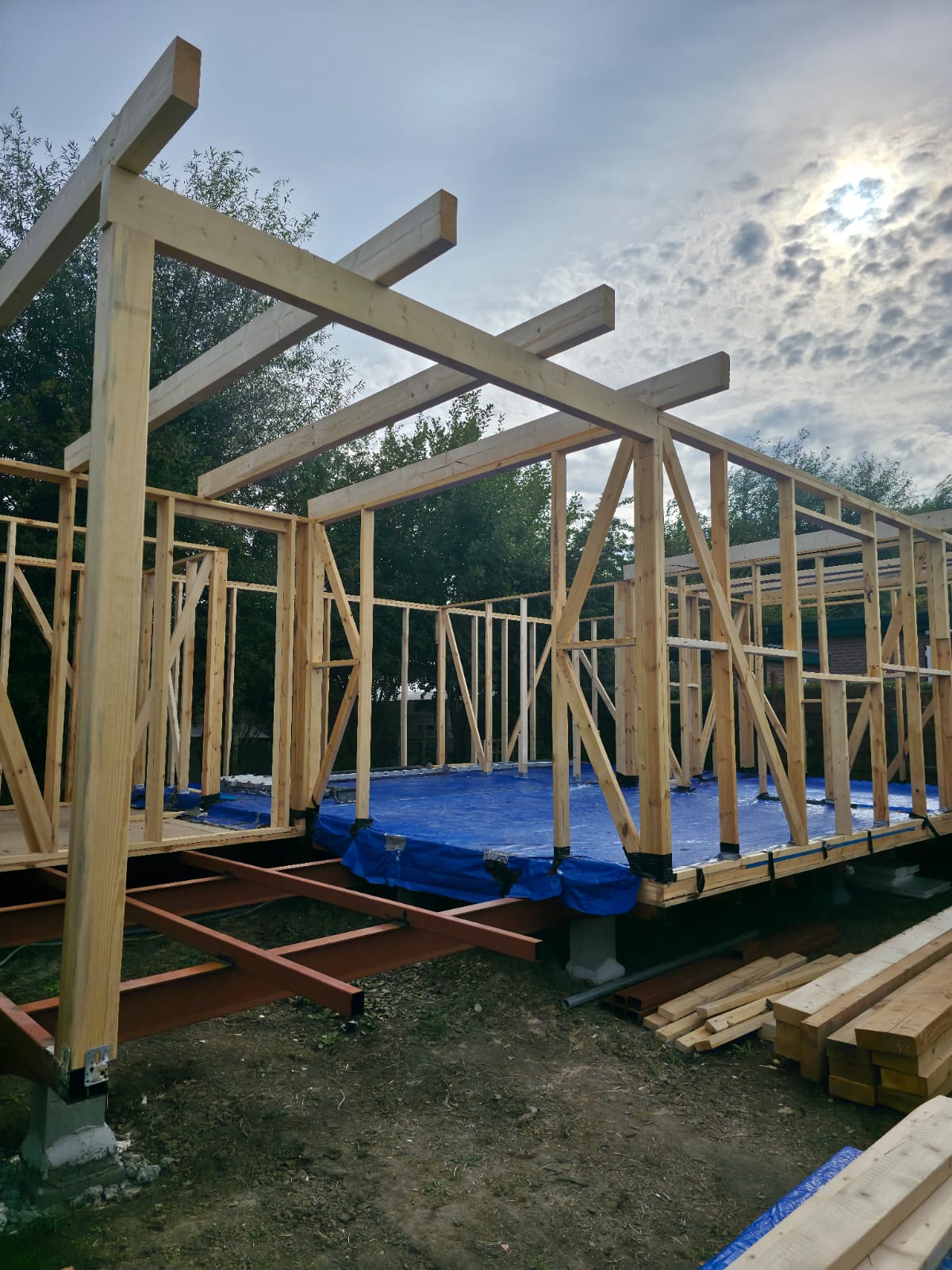 Timber roof beams being installed above the framed exterior walls